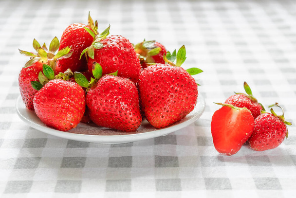 Reife Erdbeeren in einem weißen Teller auf dem Tisch - Foto, Bild
