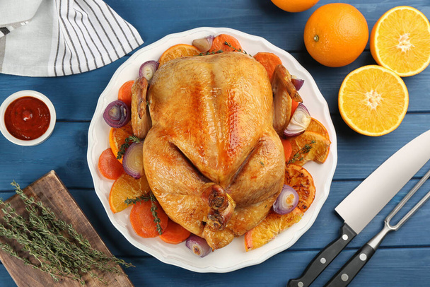 Roasted chicken with oranges on blue wooden table, flat lay - Foto, immagini
