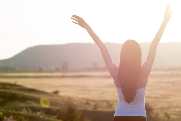 Femme encourageante bras ouverts au lever du soleil
 - Photo, image