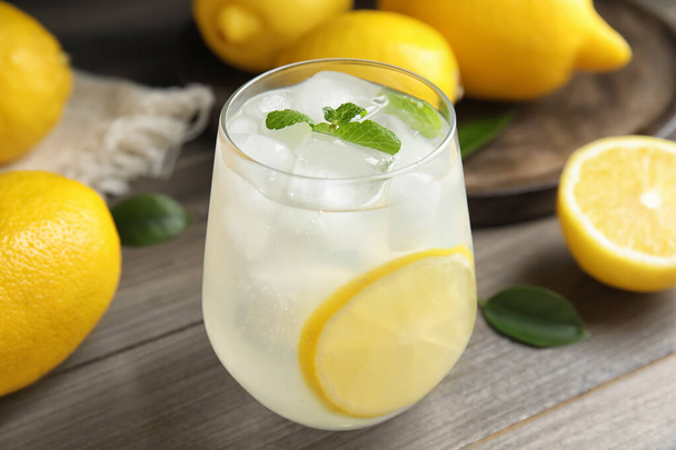 Cool freshly made lemonade in glass on wooden table, closeup - Photo, image