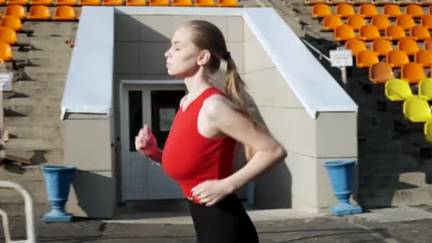 ταιριάζει καυκάσιος όμορφη γυναίκα στα αθλητικά τρέχει κατά μήκος statium tribune σε εξωτερικούς χώρους - Πλάνα, βίντεο