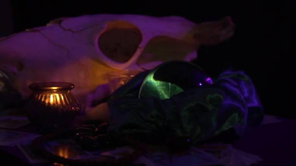 Table de tarot violet, avec les cartes, runes, la future boule de cristal, un crâne de vache et une bougie noire - Séquence, vidéo