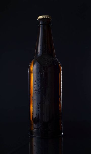 botella de cerveza sobre fondo negro botella de cerveza sobre fondo negro. Publicidad foto - Foto, imagen