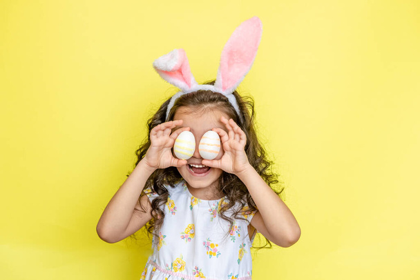 funny happy child girl with easter eggs on yellow background - Foto, Bild