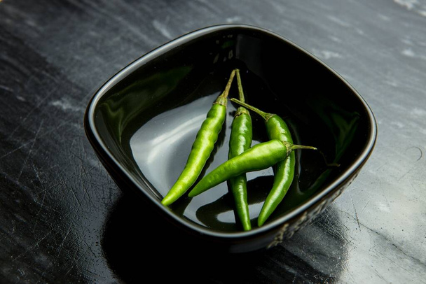 Zelené chilli papričky v černé misce na černém pozadí - Fotografie, Obrázek
