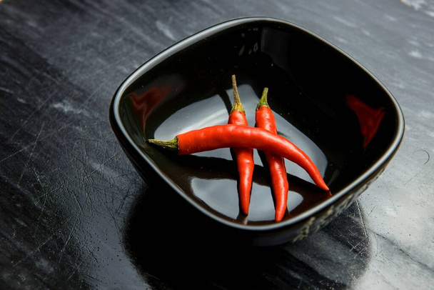 Punainen chili paprikat musta kulho mustalla pohjalla - Valokuva, kuva