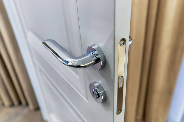Sluiten foto van witte deur met zilveren deurknop, uitzicht van boven - Foto, afbeelding