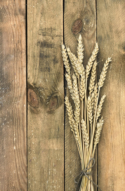Wheat spikes bouquet on wooden rustic table with copy space for your design, harvesting and eco food concept, closeup, flat lay, overhead top view, vertical - Fotó, kép