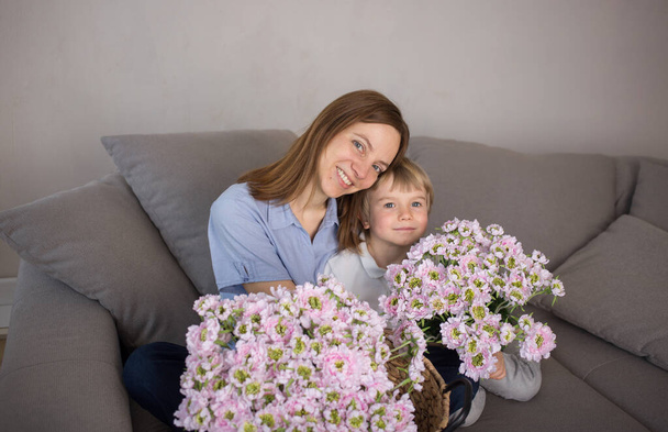 heureuses mères souriantes avec son fils avec un grand bouquet de fleurs roses, regardant la caméra. Un doux moment de famille. Concept de fête des mères. Profitez, l'amour, la joie, la maternité heureuse. Concentration sélective - Photo, image