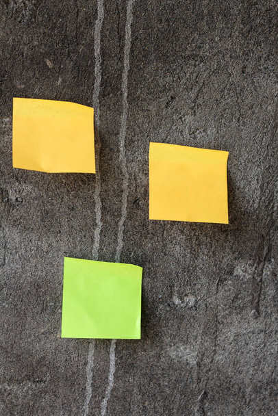 Notes collantes jaunes et vertes sur le mur gris - Photo, image