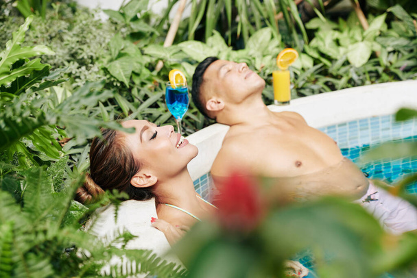 Kaunis pari rentouttava ja virkistävä uima-altaassa kuumana kesäpäivänä ja nauttia lämpimistä auringonsäteistä - Valokuva, kuva