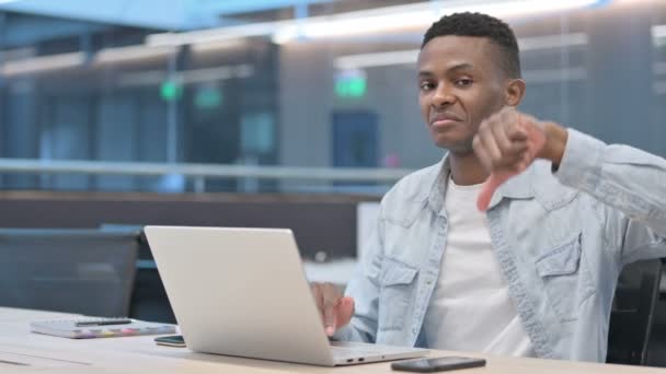 Pulgares abajo por el hombre africano con el ordenador portátil en la oficina  - Metraje, vídeo