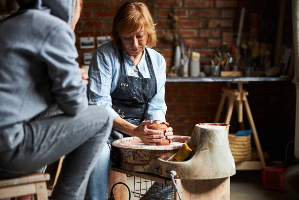 Nice elderly woman making pottery in workshop - Photo, Image