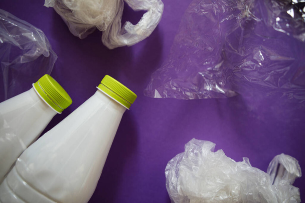 Umweltverschmutzung durch Kunststoffprodukte. Hausmüll. Plastikflaschen und -verpackungen auf lila Hintergrund. - Foto, Bild
