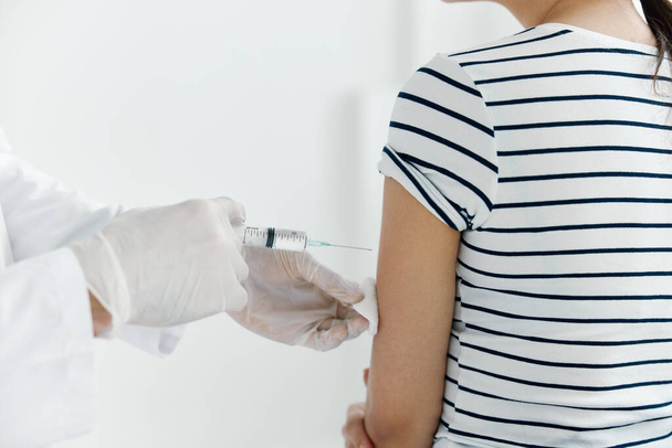 лікар з медичними рукавичками вводить вакцину у пацієнтів крупним планом
 - Фото, зображення