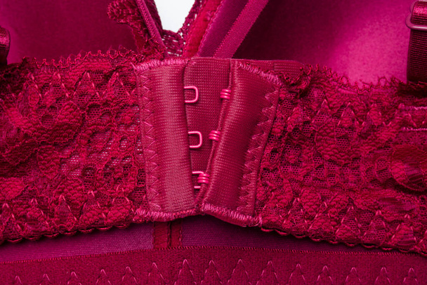 Top view close up σκούρο κόκκινο κούμπωμα σουτιέν με δαντέλα σε λευκό φόντο.Αξεσουάρ για ράψιμο εσώρουχα - Φωτογραφία, εικόνα