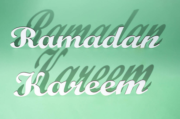 Ramadan Kareem biglietto di auguri concetto creativo fatto di intagliato bianco italico lettere 3d catturati con ombre su uno sfondo verde chiaro.  - Foto, immagini
