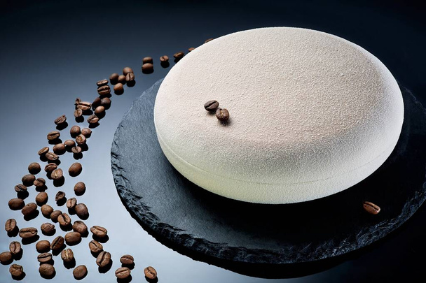 Delicate mousse cake with ground coffee beans and hazelnuts on a dark stone background - Valokuva, kuva