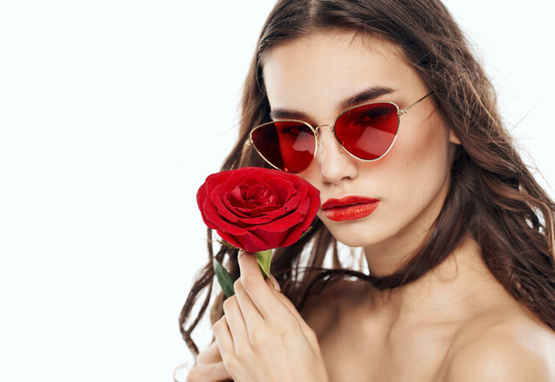 Θέα σέξυ μελαχρινή σε γυαλιά με κόκκινο λουλούδι στα χέρια - Φωτογραφία, εικόνα