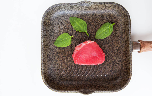 Frischer pinkfarbener Thunfisch liegt in Großaufnahme auf einer Grillpfanne. Eine köstliche und gesunde Mahlzeit - Foto, Bild