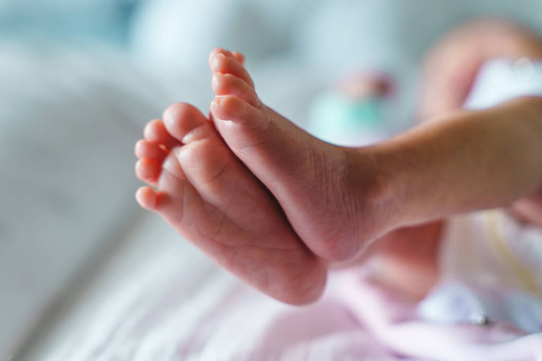 Κοντινό πλάνο στα πόδια του άγνωστου νεογέννητου μωρού που βρίσκεται στο κρεβάτι στο σπίτι με αντίγραφο χώρο - Φωτογραφία, εικόνα