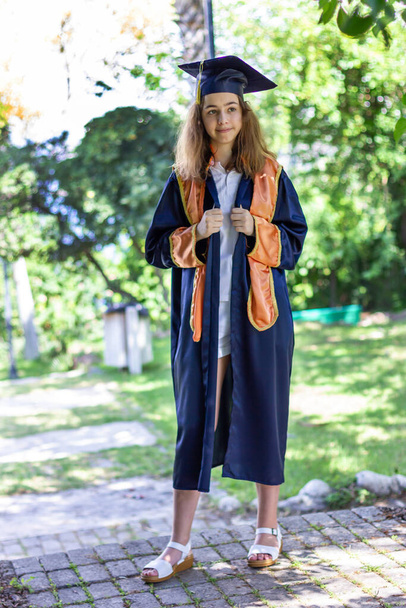 High school graduate. Schoolgirl in graduation cap and mantle. - Photo, Image