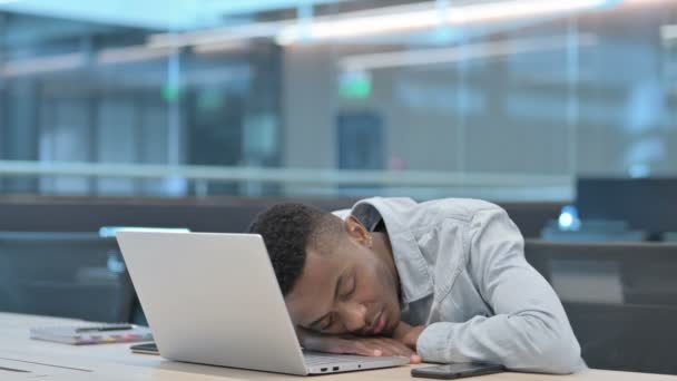 Hombre africano con portátil tomando siesta en la oficina  - Metraje, vídeo