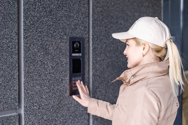 Close up the female hand presses the doorphone button. The girl is calling the intercom. Means of communication or notification of arrival and security of the entrance inside - Photo, Image