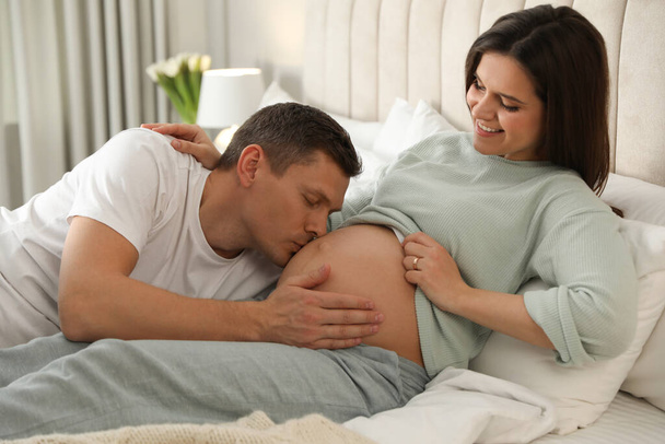 Young pregnant woman with her husband in bedroom - Foto, Imagen