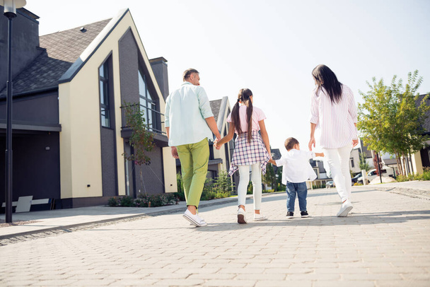 Full length body size rear back behind view of nice adorable family walking with kids holding hands spending time cottage town outdoor - Zdjęcie, obraz