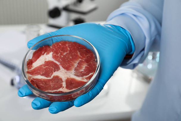 Scientist holding Petri dish with cultured meat in laboratory, closeup - Foto, afbeelding
