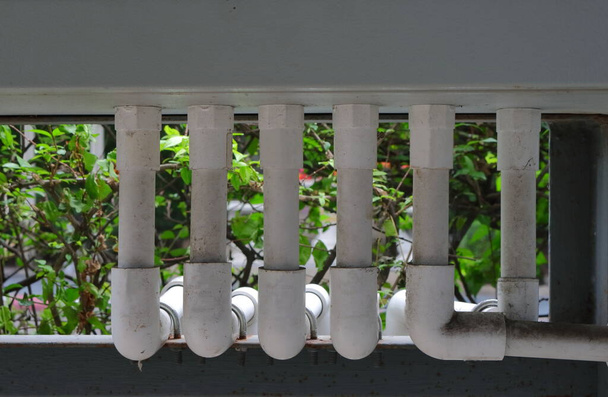 Fila de fechamento de tubos elétricos de PVC pintados com cor branca conectada ao quadro de interruptores e fixados à barra de metal, foco seletivo - Foto, Imagem