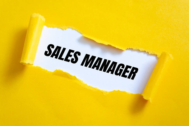 Papel amarillo desgarrado sobre superficie blanca con palabras de "Sales Manager". - Foto, Imagen