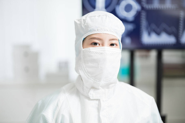 asian biotechnology researcher wearing cleanroom clothes is looking at you in the laboratory - Фото, изображение