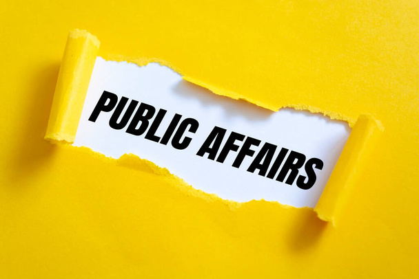 Roztrhaný žlutý papír na bílém povrchu se slovy Public Affairs. - Fotografie, Obrázek