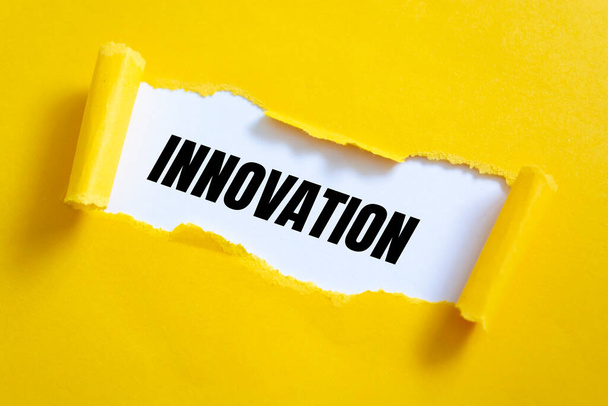 Libro amarillo desgarrado sobre superficie blanca con palabras de innovación. - Foto, Imagen