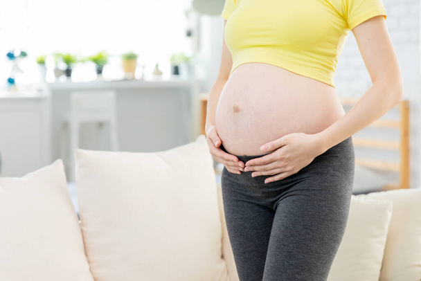 close up of pregnant women belly in living room - Fotó, kép