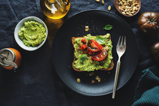 Tasty sandwich on wholegrain bread with mashed avocado and tomatoes. Closeup.  - Foto, Imagen