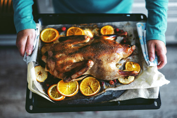 Frau kocht Ente mit Gemüse und putzt sie aus dem Ofen. Lebensstil. Weihnachts- oder Erntedankkonzept.  - Foto, Bild