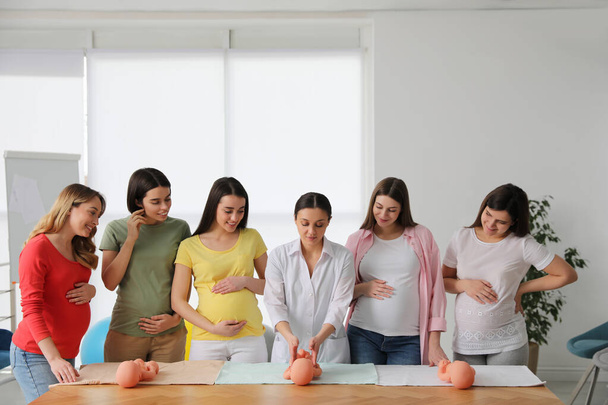Pregnant women learning how to swaddle baby at courses for expectant mothers indoors - Photo, image