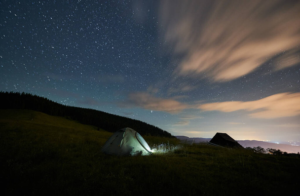 Вид на пейзаж туристической палатки возле леса под звездным небом. Кто-то ночует в горах. Понятие природы. - Фото, изображение