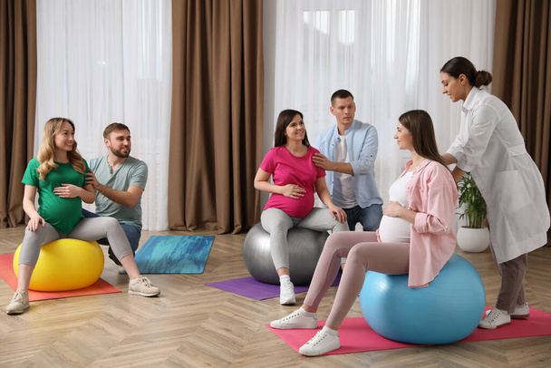 Pregnant women with men and doctor at courses for expectant parents indoors - Foto, Imagem