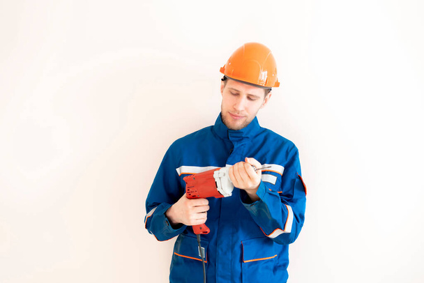 νέος άνδρας εργάτης με στολή που κρατά το ηλεκτρικό εργαλείο - Φωτογραφία, εικόνα