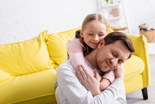happy father and daughter with closed eyes embracing at home - Fotoğraf, Görsel