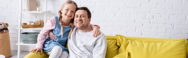 allegro padre e figlia che si abbracciano sul divano a casa, striscione - Foto, immagini