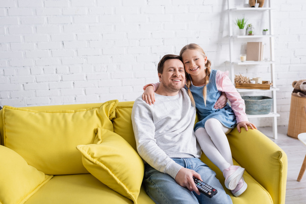 feliz padre e hija viendo la televisión en el sofá en casa - Foto, imagen