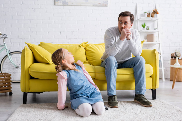 cheerful father and daughter grimacing while looking at each other at home - Foto, afbeelding