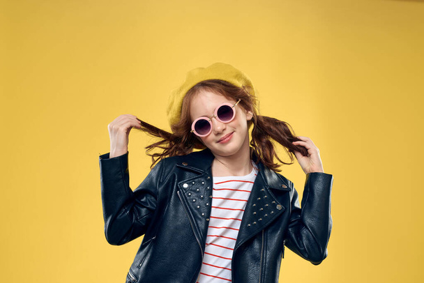 Cheerful little girl in sunglasses and hat lifestyle studio yellow background fashion - Fotografie, Obrázek