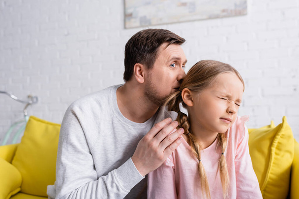 dad kissing head of offended daughter sitting with closed eyes - Foto, Imagen