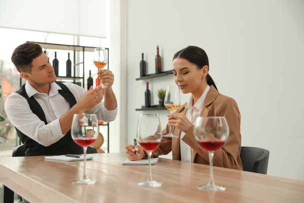Sommeliers proeven verschillende soorten wijn aan tafel binnen - Foto, afbeelding